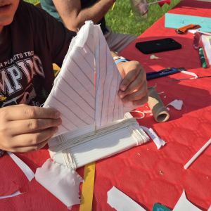 Rodzinne Spotkania ze Sztuką - WYPŁYWAMY NA SPOTKANIE LATA! - zdjęcie przedstawia uczestnika przygotowującego łódkę z papieru
